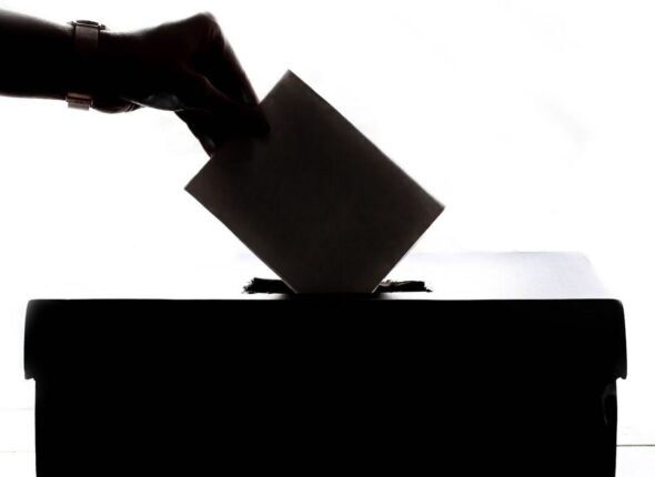 Main glissant un bulletin de vote dans une urne, symbole de l'élection des membres du CSE