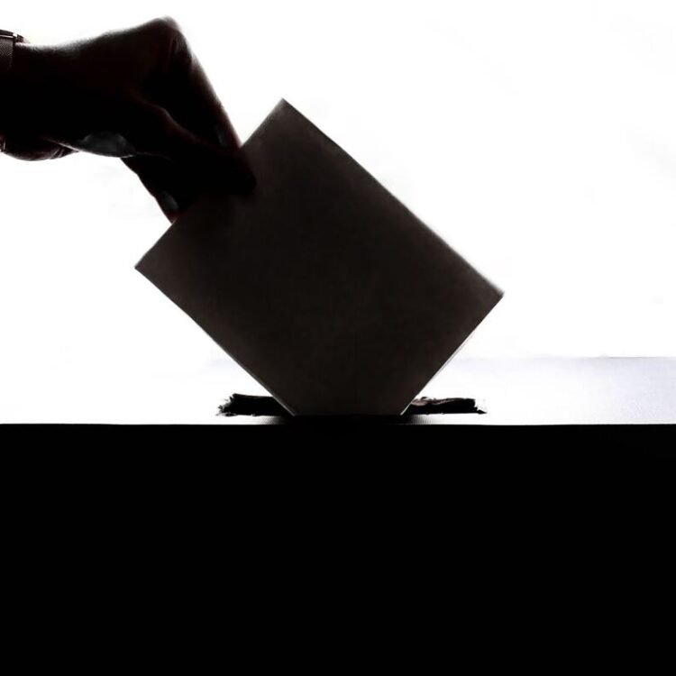 Main glissant un bulletin de vote dans une urne, symbole de l'élection des membres du CSE