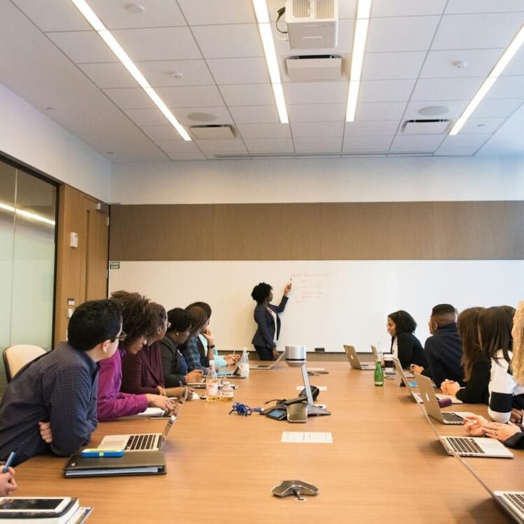 Membres d'un comité réunis autour d'une grande table de réunion, face à une présentation