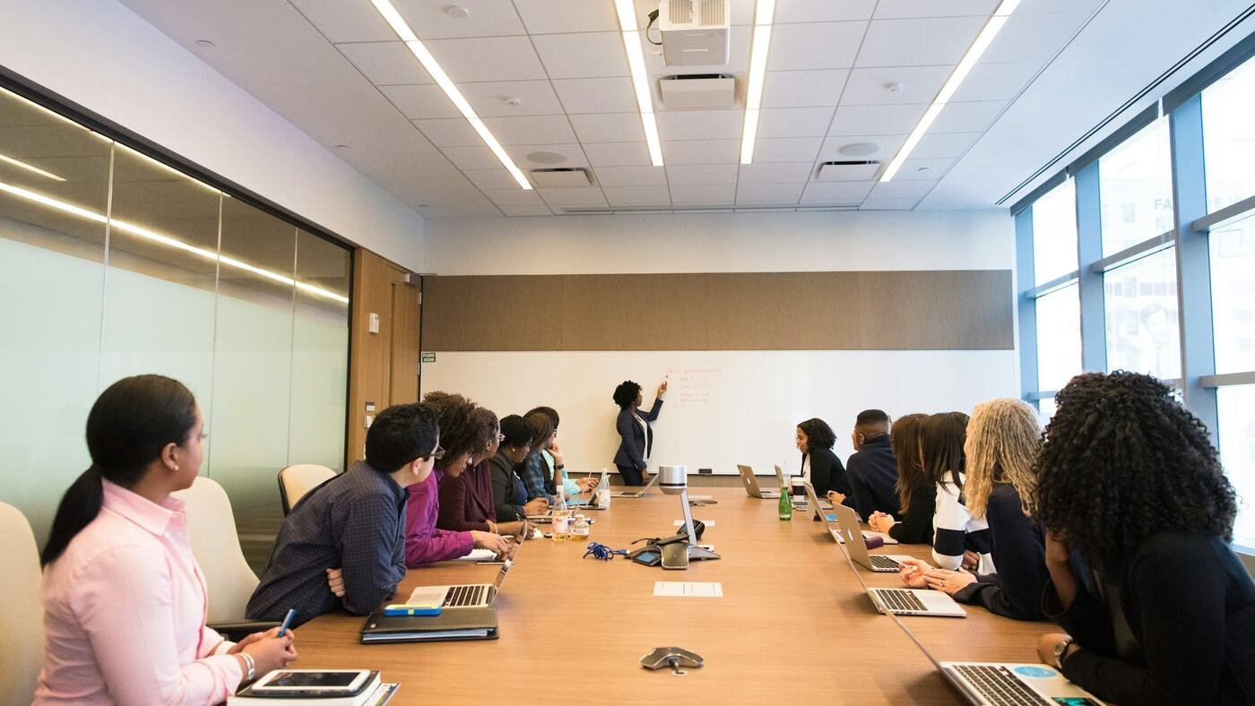 Membres d'un comité réunis autour d'une grande table de réunion, face à une présentation
