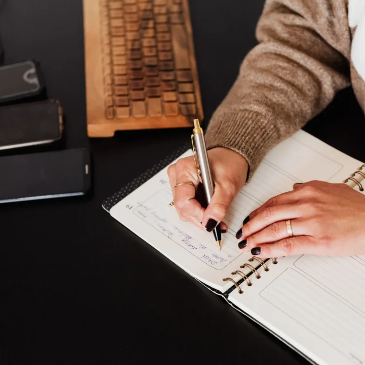 Main notant une échéance dans un agenda à spirale, près d'un clavier en bois : anticiper le délai de convocation du CSE